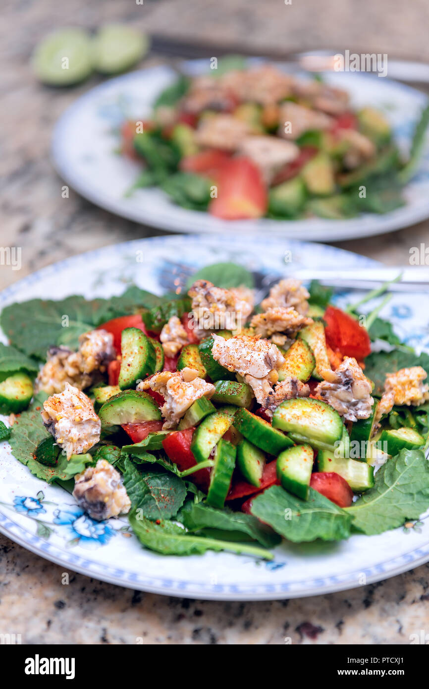 Deux Plaques Avec Bebe Chou Frise Vert Sain Avec Salade De Concombres De Tomates Raisins De Tempeh De L Assaisonnement Pour Chili Et Le Sel Repandu Sur Le Comptoir De Cuisine En Granit