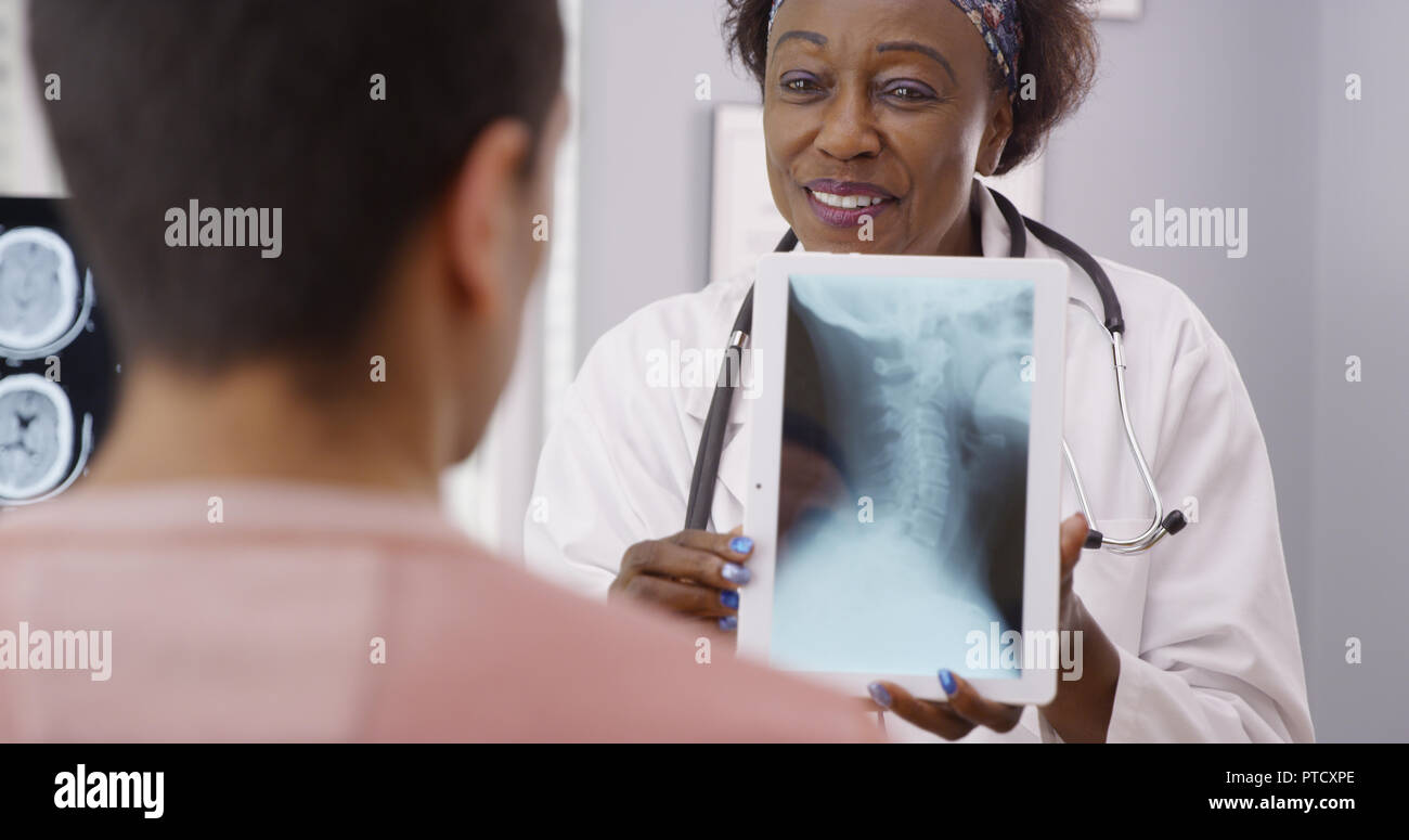 La haute charme médecin noir pointant vers la source des patients la douleur au cou sur x ray Banque D'Images