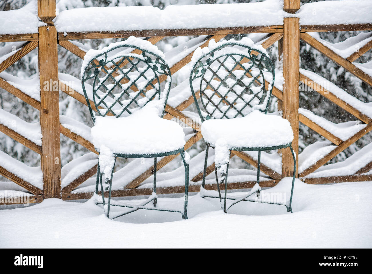Terrasse en bois de la maison avec deux chaises en métal vert jardin quartier avec plancher de bois couverte de neige pendant la tempête de blizzard, blanc, des flocons de f Banque D'Images