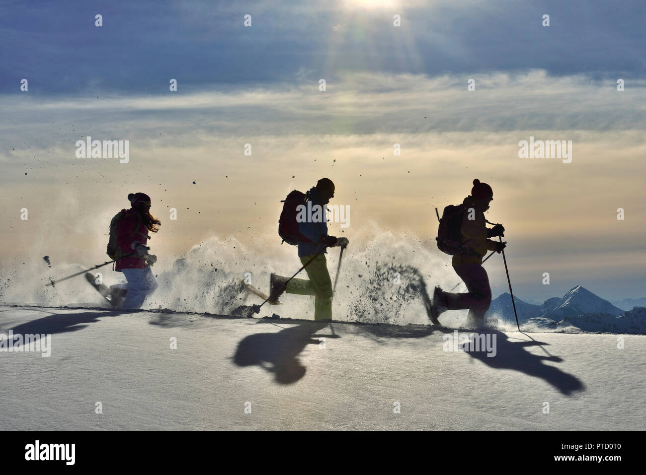 Trois randonneurs en raquettes courir dans la neige contre la lumière, le tour de l'Fellhorn, Reit im Winkl, Smiling, Portrait Banque D'Images