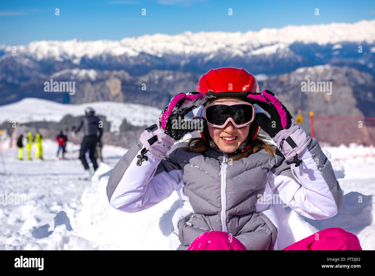 Petite fille assise dans la neige portant des lunettes de ski Banque D'Images