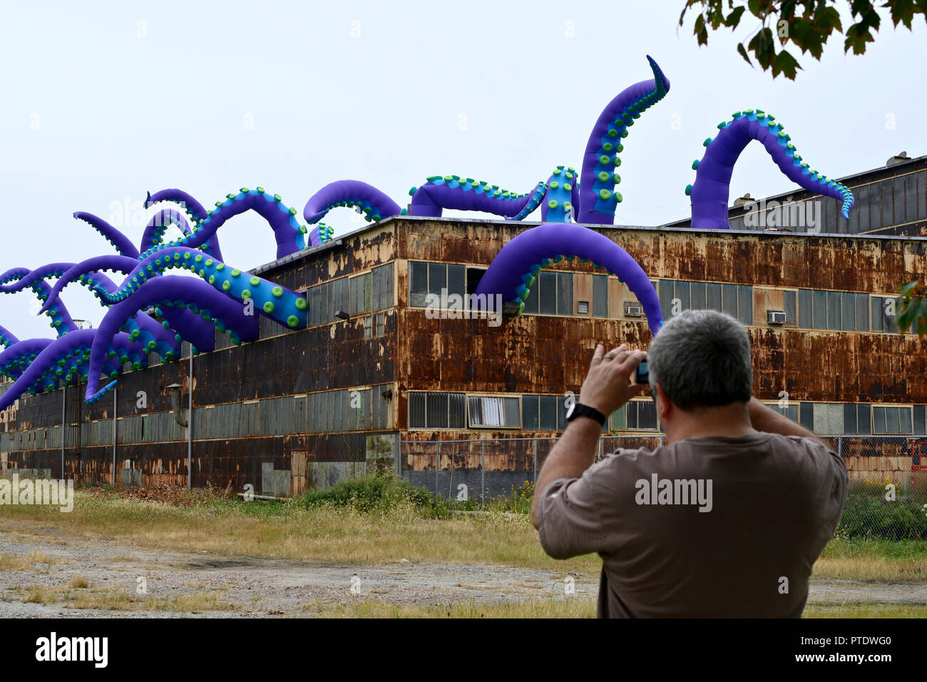 Philadelphie, USA. 8 octobre 2018. Tentacules gonflable d'une installation d'art temporaires, intitulé Navy Yard monstre de mer, par l'artiste anglais Pedro Estrellas et Filthy Luker émerger d'un ancien entrepôt à Philadelphie, Pennsylvanie, le 8 octobre 2018. L'œuvre d'art est commandé par la Société de développement industriel de Philadelphie pour promouvoir le réaménagement des Philadelphia Navy Yard. Credit : PhotograPHL/Alamy Live News Banque D'Images