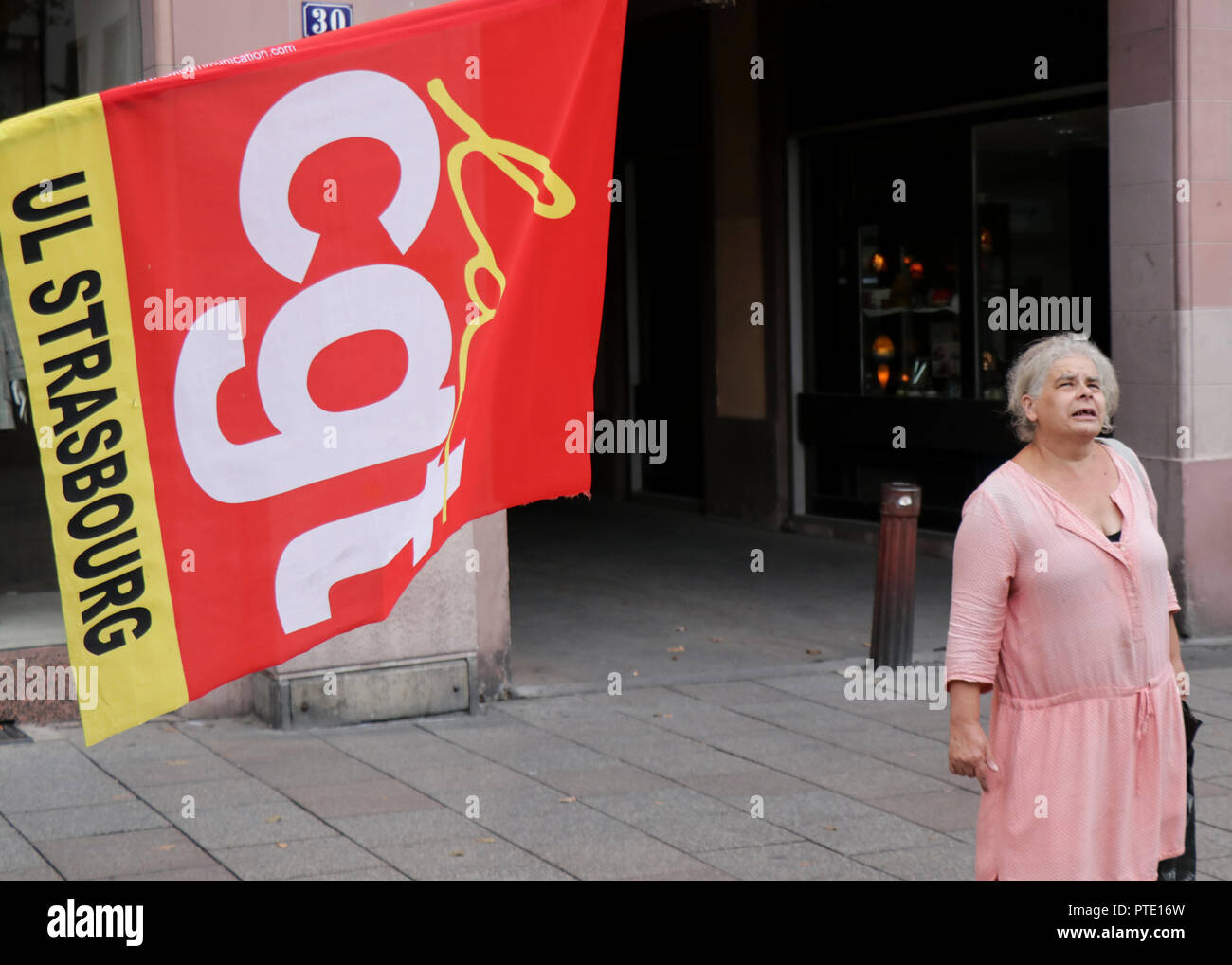 Une dame âgée vu debout à côté d'un drapeau pendant la manifestation. Les gens démontrer pendant une journée de grève nationale, plus de Président français Emmanuel Macron's policies in Strasbourg, France. Banque D'Images