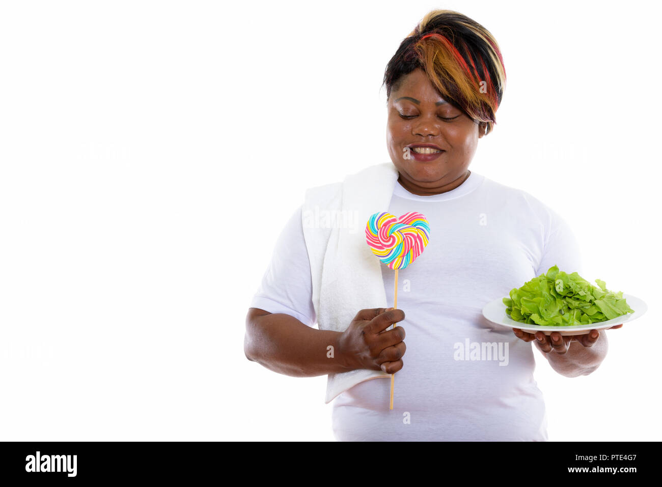 Studio shot of happy fat black African woman smiling while holdi Banque D'Images