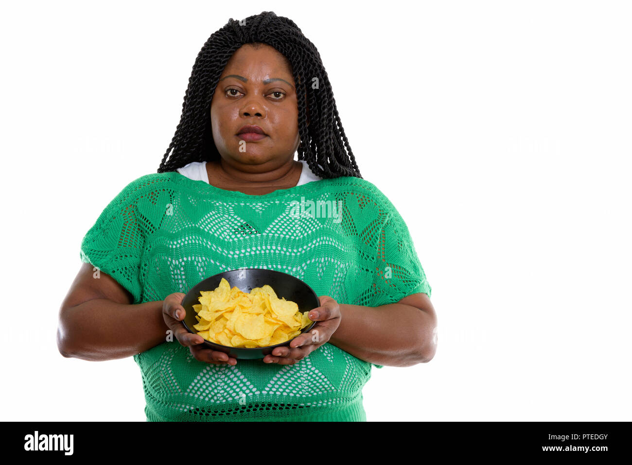 Studio shot of fat black African woman holding bowl of potato ch Banque D'Images