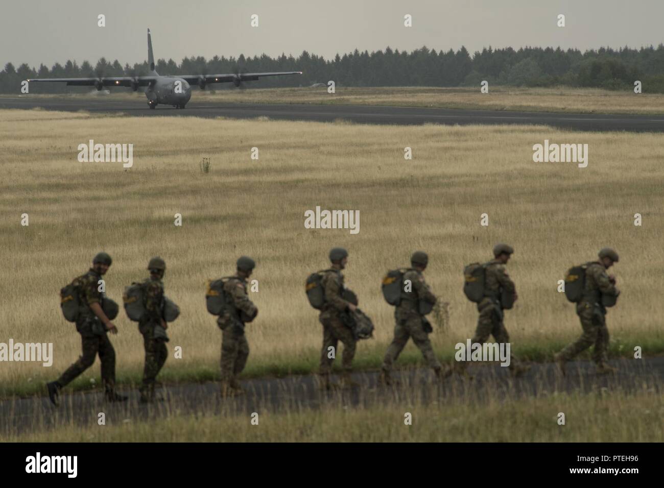 Plusieurs pays de l'OTAN de parachutistes à pied vers un U.S. Air Force C-130J Super Hercules à bord pendant la Semaine internationale Jump plus de Bitburg, en Allemagne, Juillet 11, 2017. Environ 500 militaires de plus de 13 pays partenaires ont participé à cette année de formation. Banque D'Images