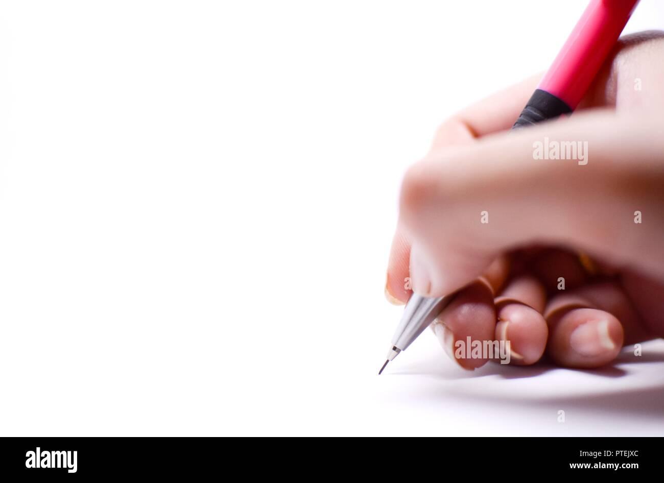 La main d'une femme est en train d'écrire quelque chose avec un crayon rose, isolé sur fond blanc. Il y a l'espace vide sur le côté gauche qui devrait être utilisé Banque D'Images