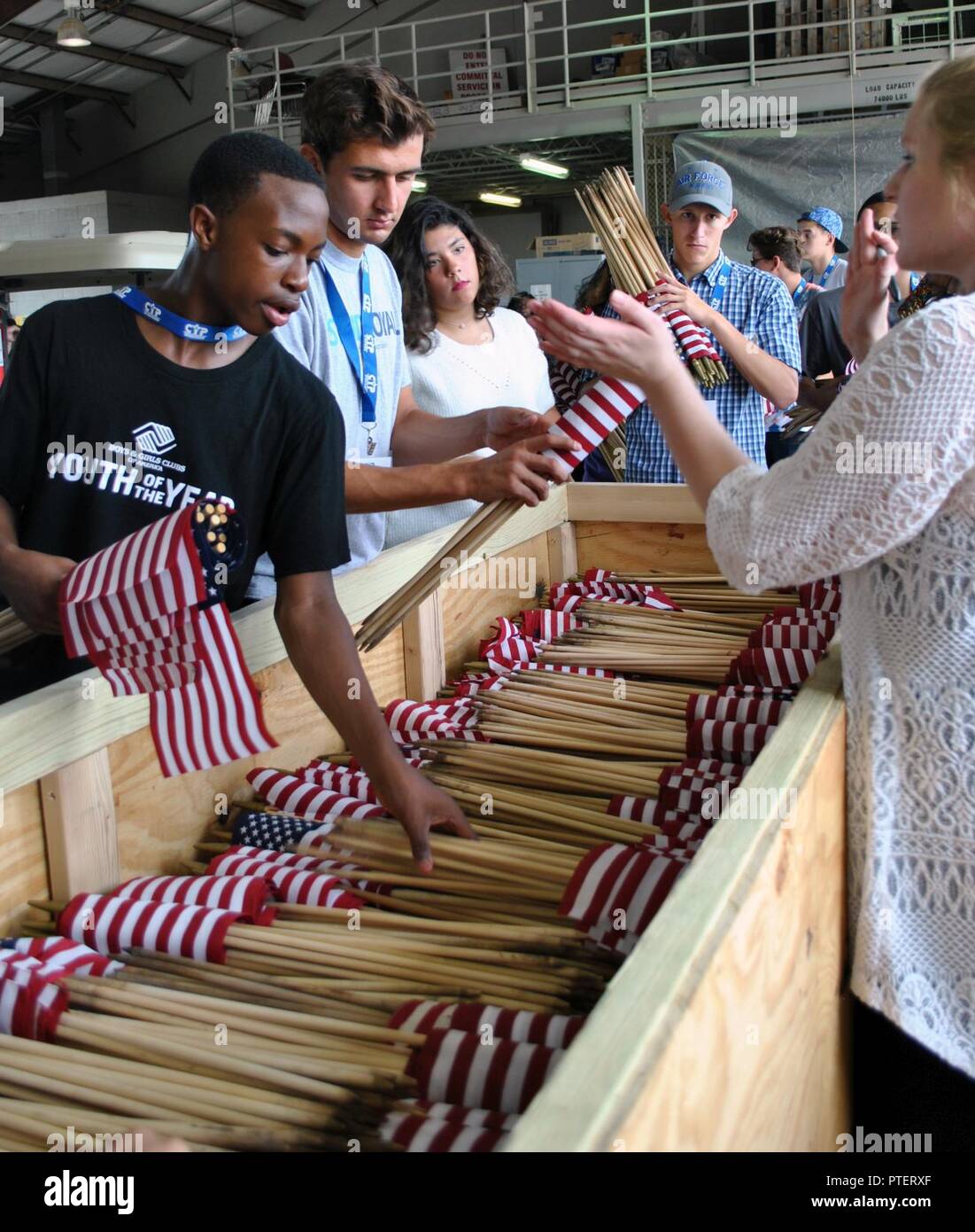 Victor, Oluwagbemi Joint Base McGuire-Dix-Lakehurst, New Jersey, les jeunes de l'année ; et l'Armée de l'air les membres du conseil des ados Andrew Smith, Jamie Butikofer et Dawson Gildig drapeaux dans un lieu de stockage. Chaque année au cours de la jeunesse de l'Armée de l'air de l'année et au Sommet du Conseil de l'adolescence, les participants effectuent le service communautaire. Cette année, ils ont mis les drapeaux qui avaient été affichées durant le week-end du Memorial Day au cimetière national de Fort Sam Houston sur Joint Base San Antonio, Texas. En quelques heures le 12 juillet 2017, elles sont intégrées et stockées 35 000 drapeaux. Banque D'Images