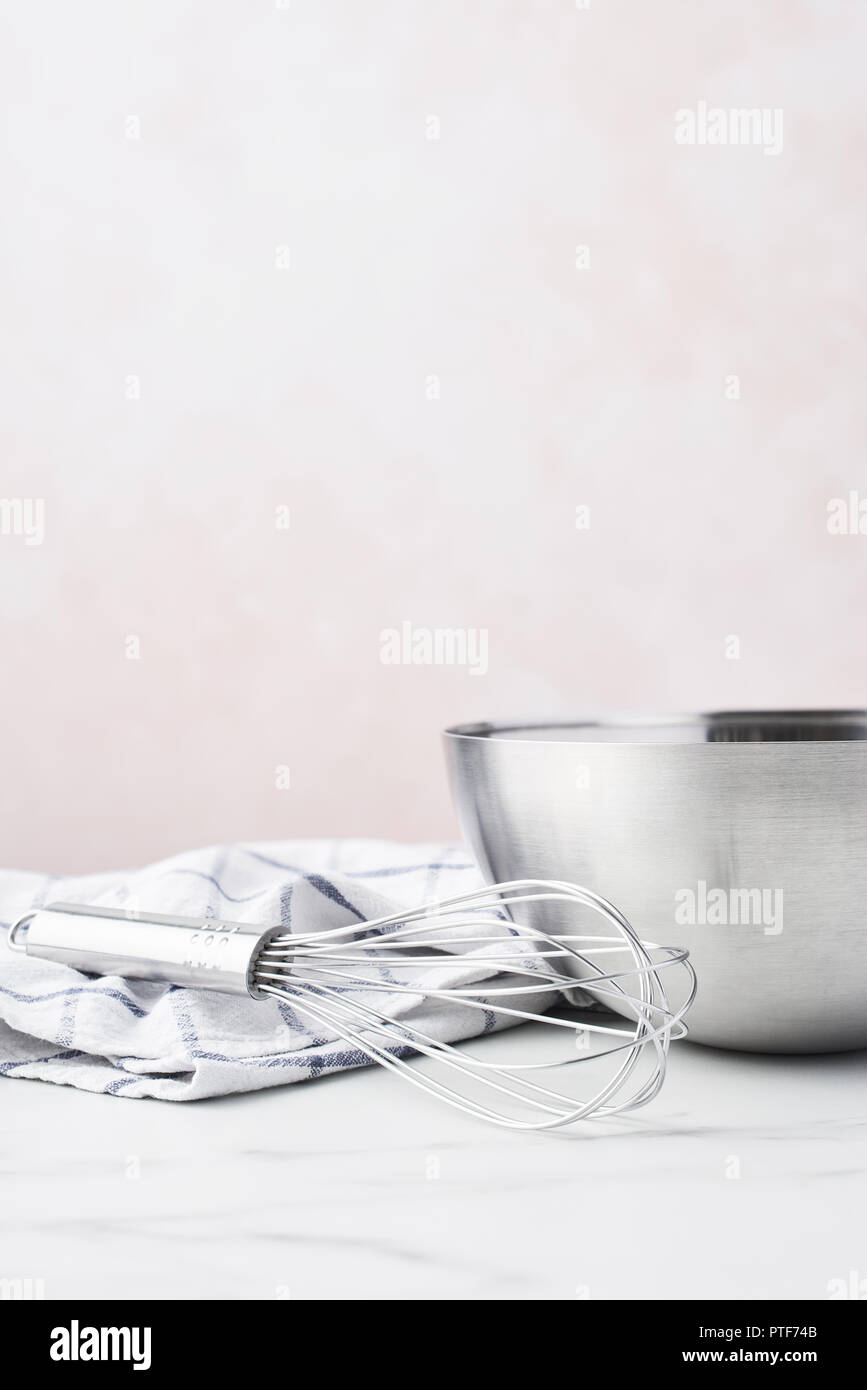 Concept de cuisson. Bol avec un fouet et table en marbre blanc sur torchon sur fond rose avec copie espace. Banque D'Images