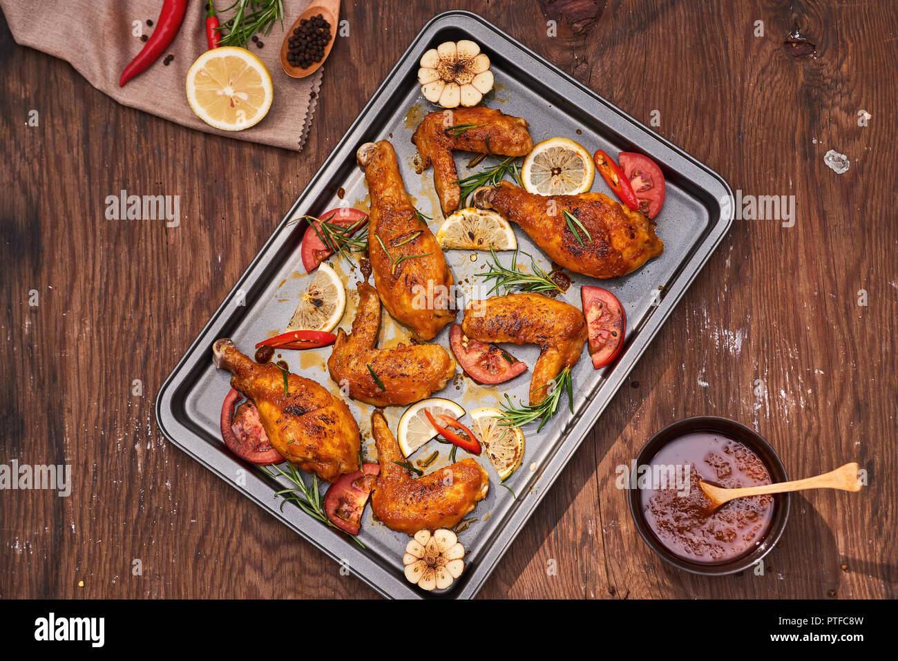 Pilons de poulet grillé et les ailes sur la plaque de cuisson sur table en bois Banque D'Images