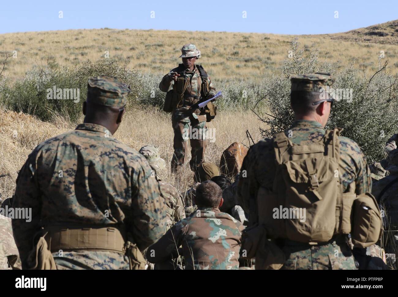 Un membre de la Force de défense nationale sud-africaine indique à Marines des États-Unis à partir de la 3e Bataillon, 25e Régiment de Marines et de soldats sud-africains à partir de la marine sud-africaine, Maritime flotte de réaction de survie terrain Bush le 19 juillet 2017, au cours de l'exercice 2017 de l'Accord commun à l'armée sud-africaine Centre d'instruction au combat de Lohatla, Afrique du Sud. Banque D'Images