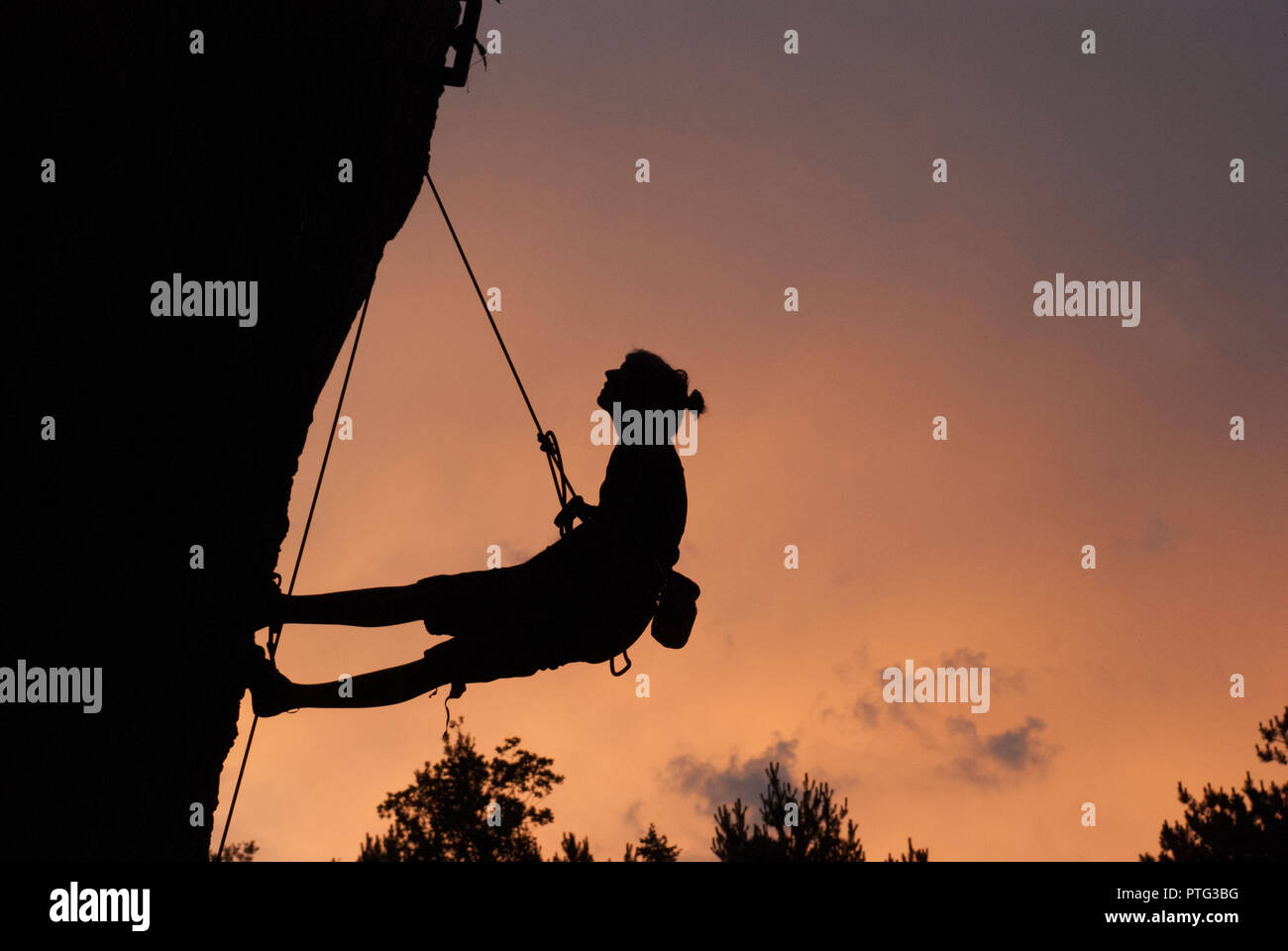 Escalade silhouette de femme au crépuscule. Banque D'Images