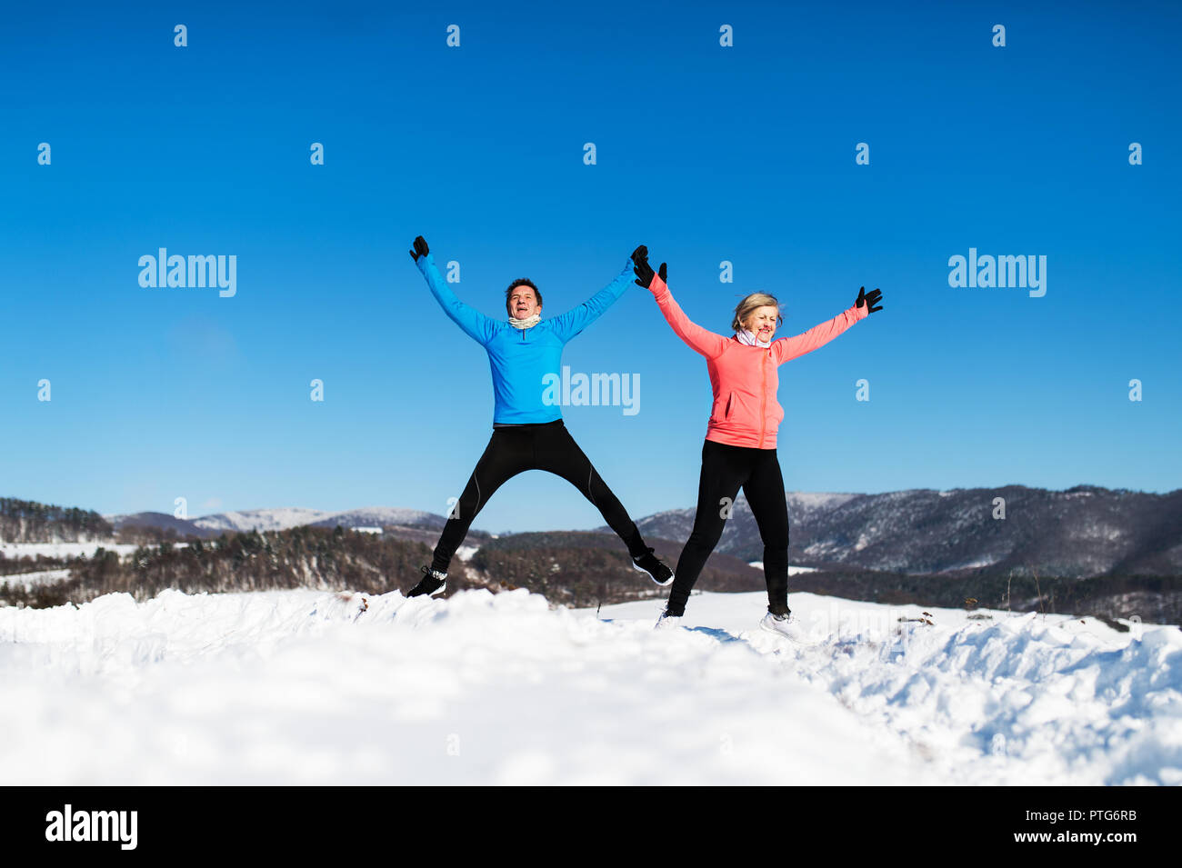 Happy senior couple porteur sautant en hiver la nature. Banque D'Images
