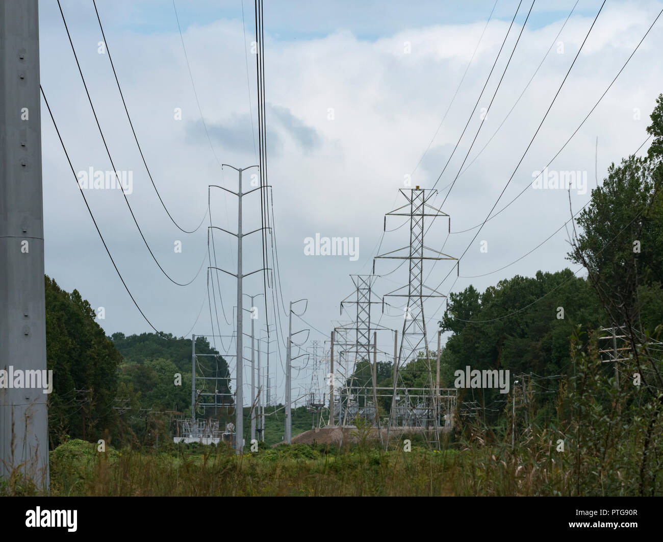 Deux rangées de poteaux d'électricité et une sous-station électrique sous un ciel nuages Banque D'Images