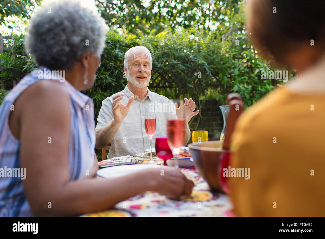 Senior friends enjoying lunch, parler à table patio Banque D'Images