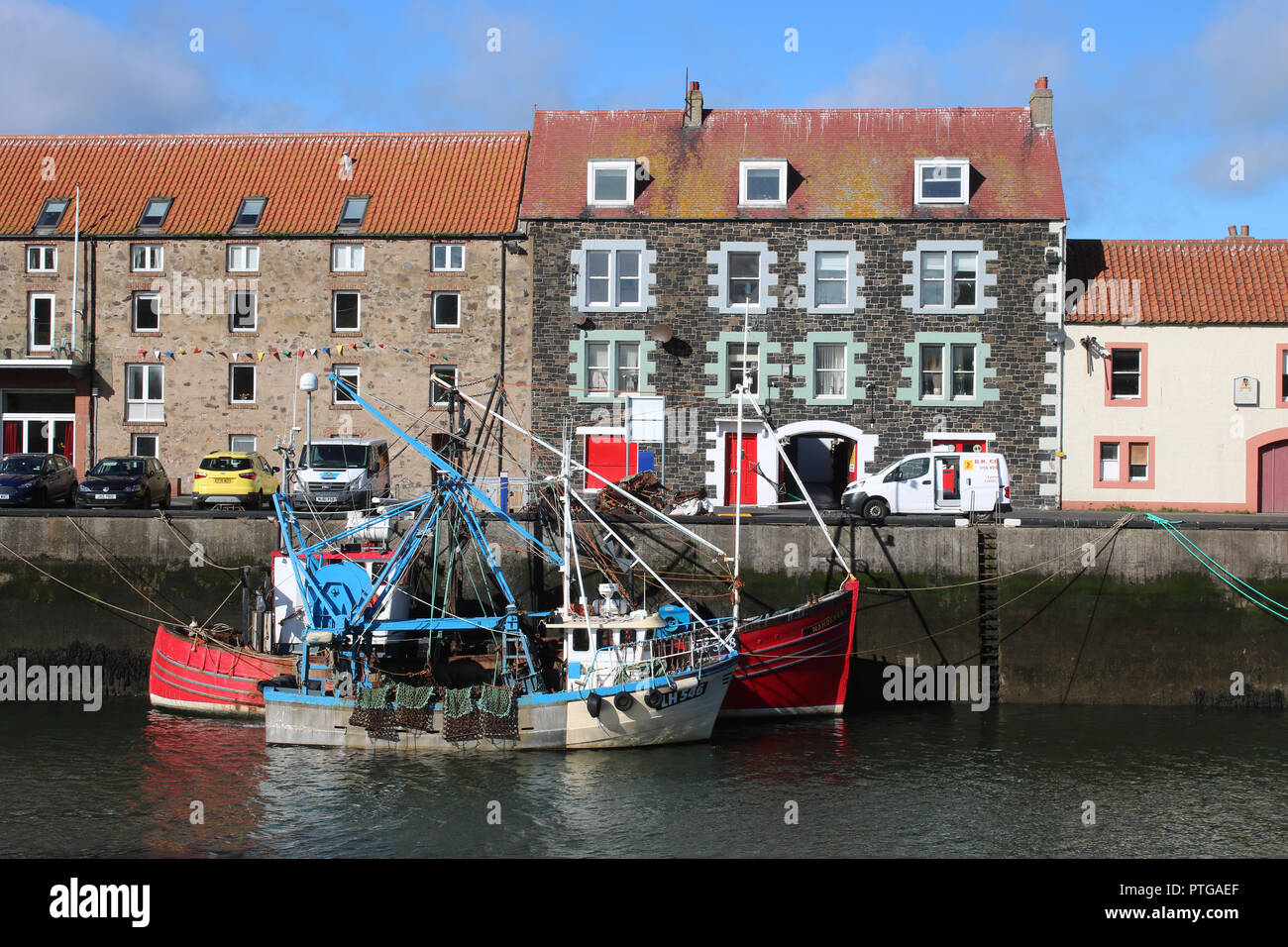 Deux petits bateaux de pêche amarrés à quai dans le port de Eyemouth, Eyemouth, en Écosse avec les bâtiments de l'autre côté de la route le long du quai. Banque D'Images