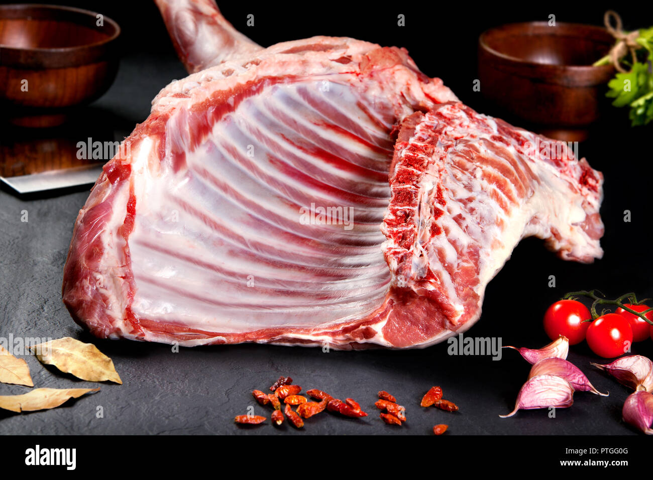 Produits frais et de la viande crue. Côtes et côtelettes de viande pour la cuisson sur fond noir avec des tomates Banque D'Images