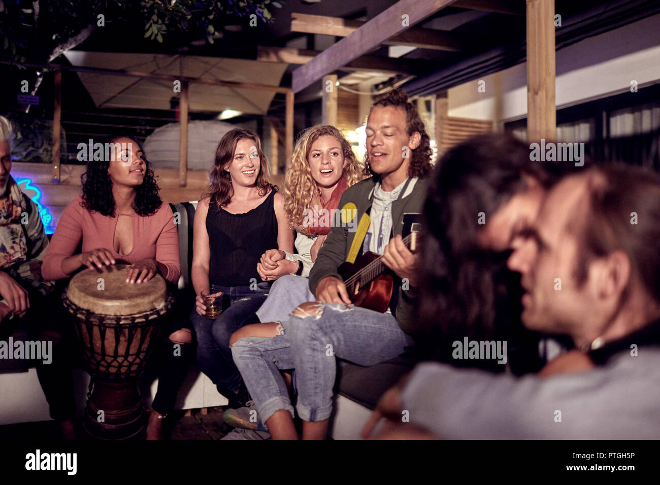 Amis, jouer de la musique sur patio de nuit Banque D'Images