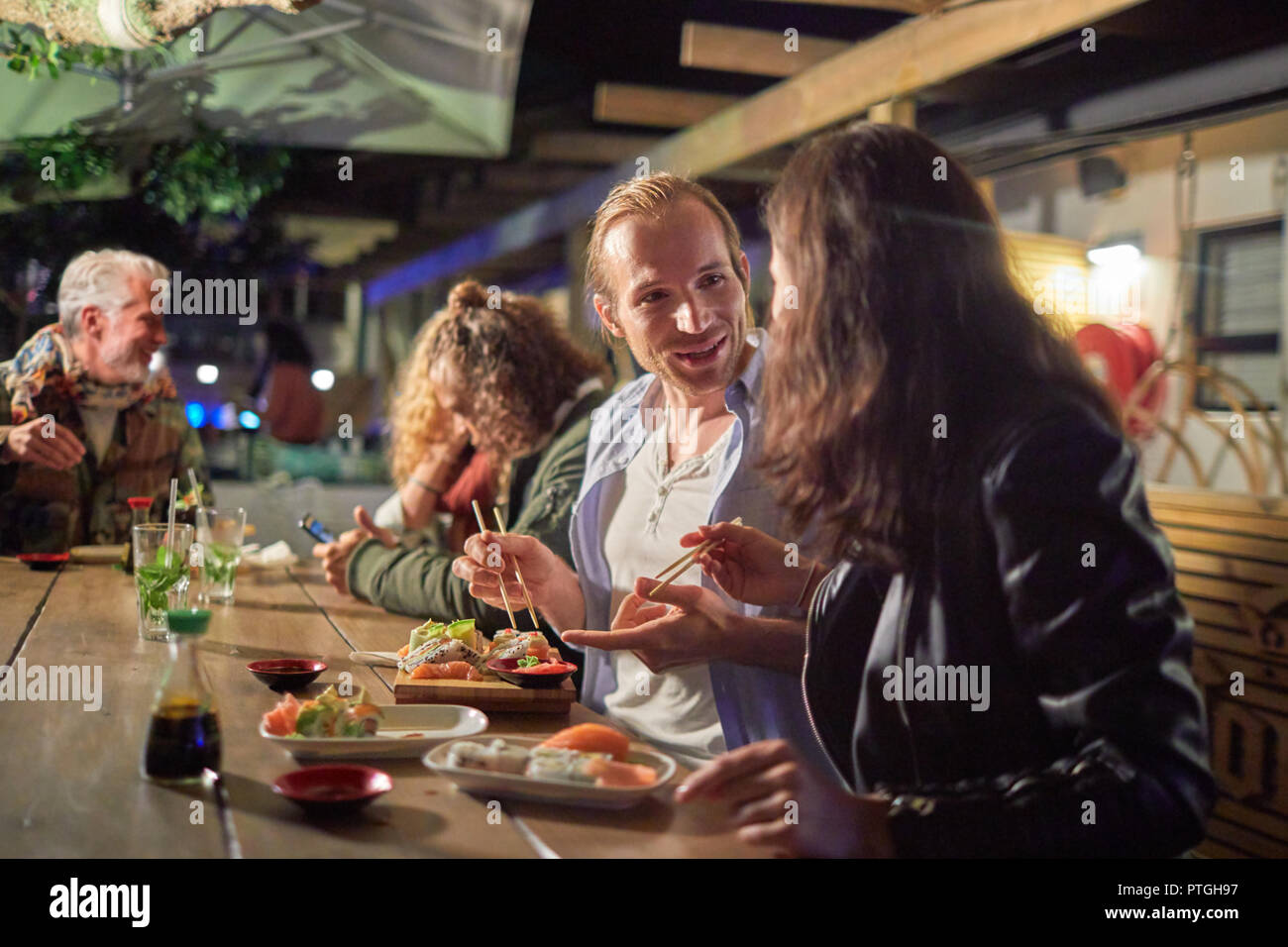 Couple eating sushi, bénéficiant d'un patio sur la nuit Banque D'Images