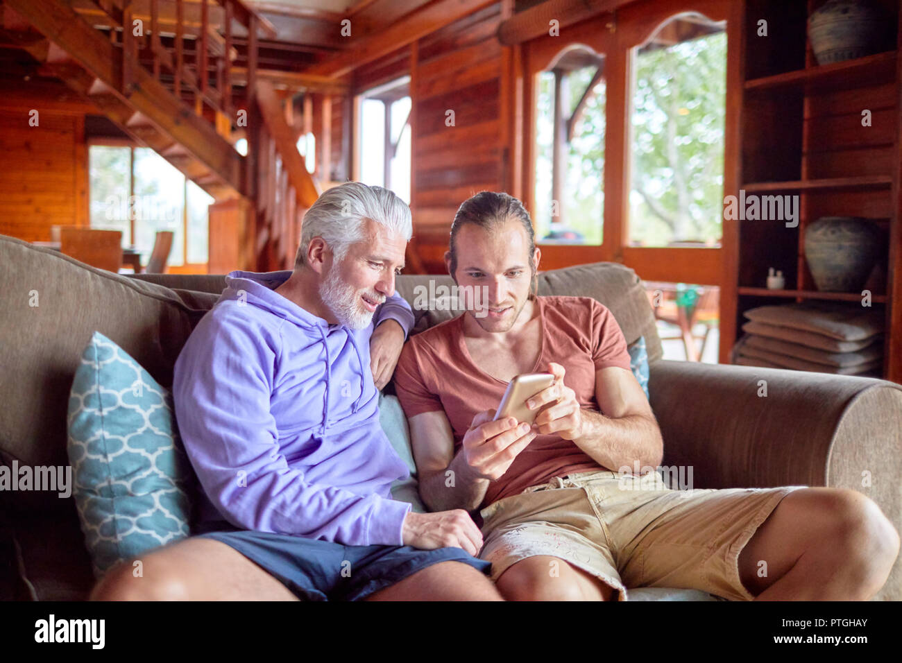 Père et fils à l'aide de smart phone sur canapé cabine Banque D'Images