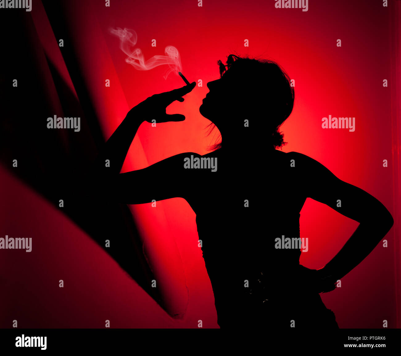 Silhouette de femme qui fume. Profil de femme tirant la fumée sur fond rouge Banque D'Images