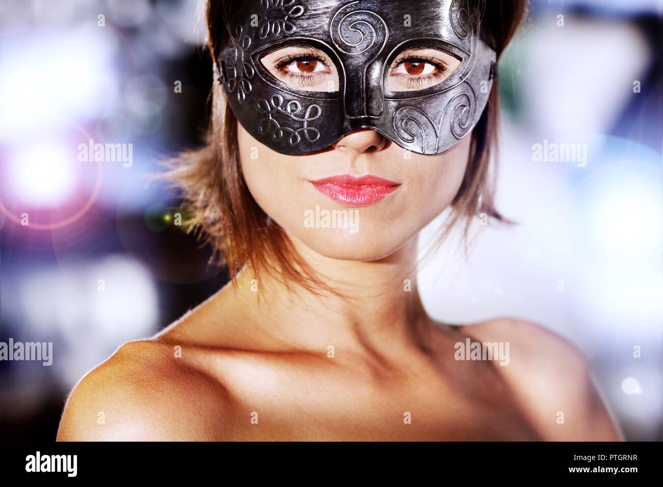 Portrait de la belle et mystérieuse femme avec masque de carnaval avec les lumières de la ville historique. Banque D'Images