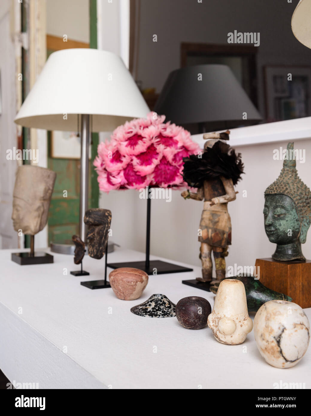 Table de plâtre blanc avec plume rose 1940 hat, égyptienne mace généraux, Native American Indian Kachina doll et un buste cambodgien Ankor. Banque D'Images