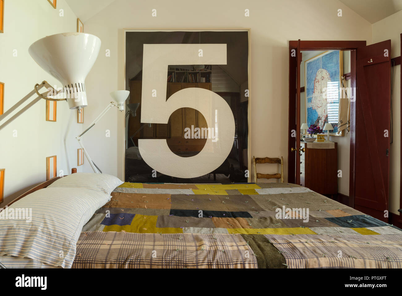 Shaker lit avec couette faite de morceaux de tissu d'habillement avec imprime par Daniel Buren. No 5 gravure sur bois par Jonathan Borofsky et paire de lampes blanches par L Banque D'Images