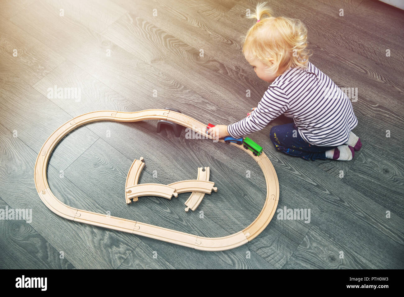 Little girl Playing with wooden railway sur marbre à la maison Banque D'Images
