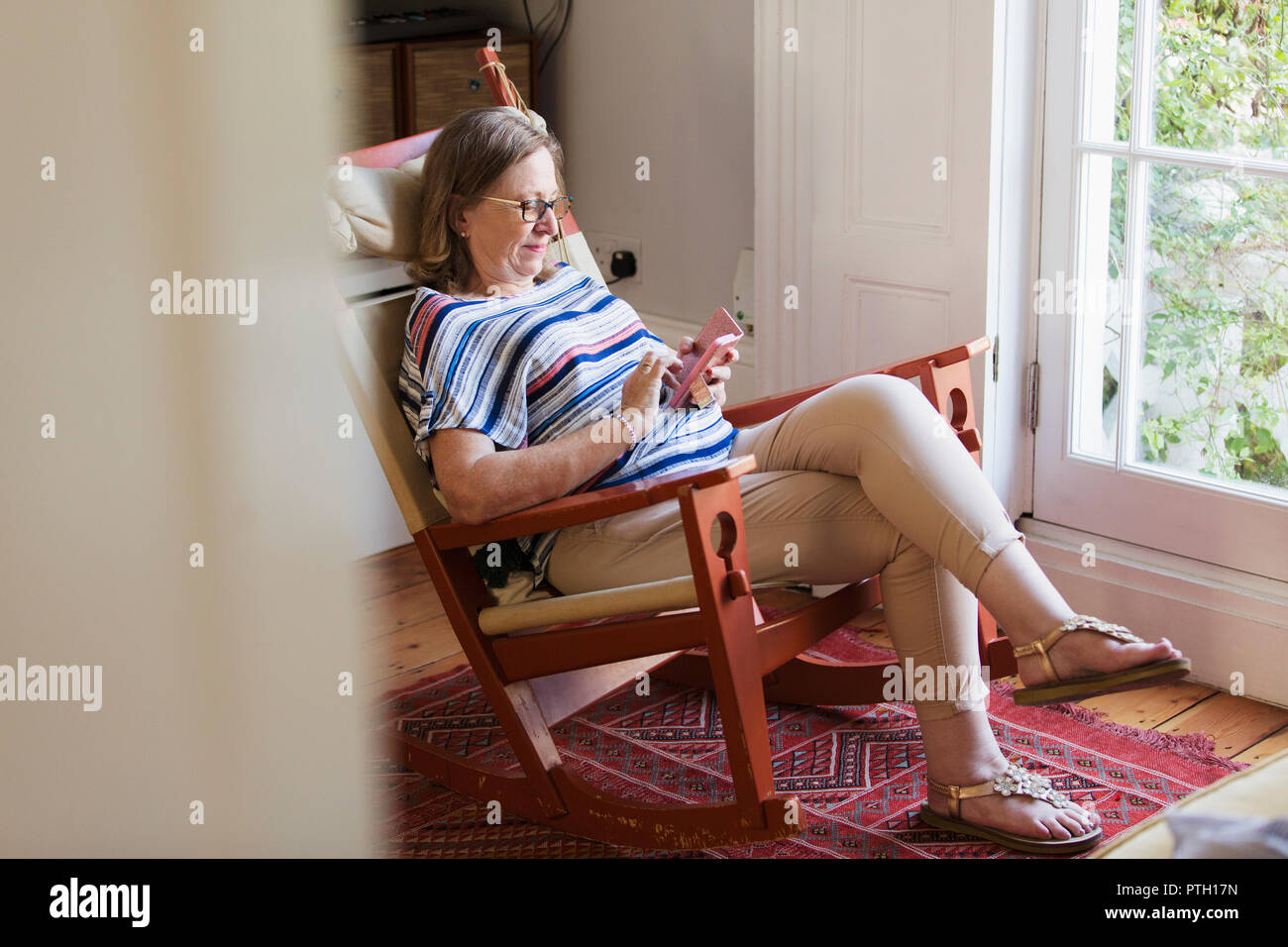 Senior woman texting with smart phone en fauteuil à bascule Banque D'Images