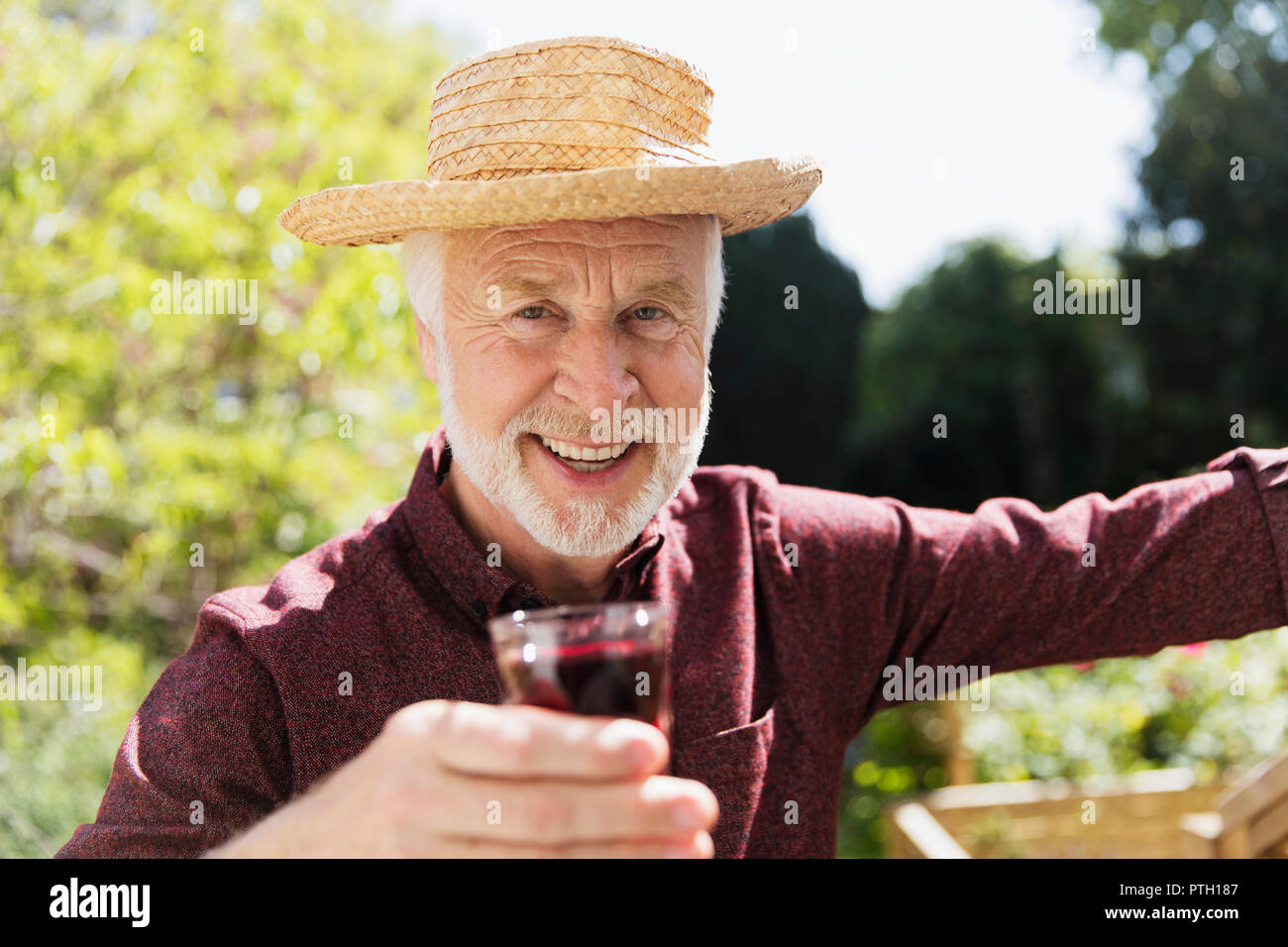 Portrait confiant senior man drinking red wine in garden Banque D'Images