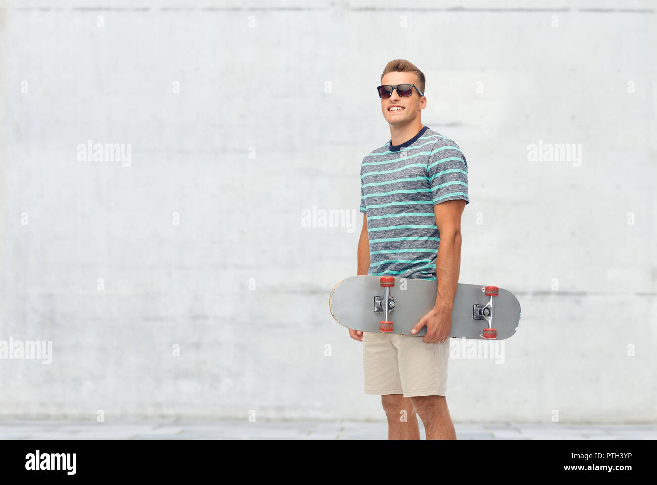 Smiling Young man with skateboard over white Banque D'Images