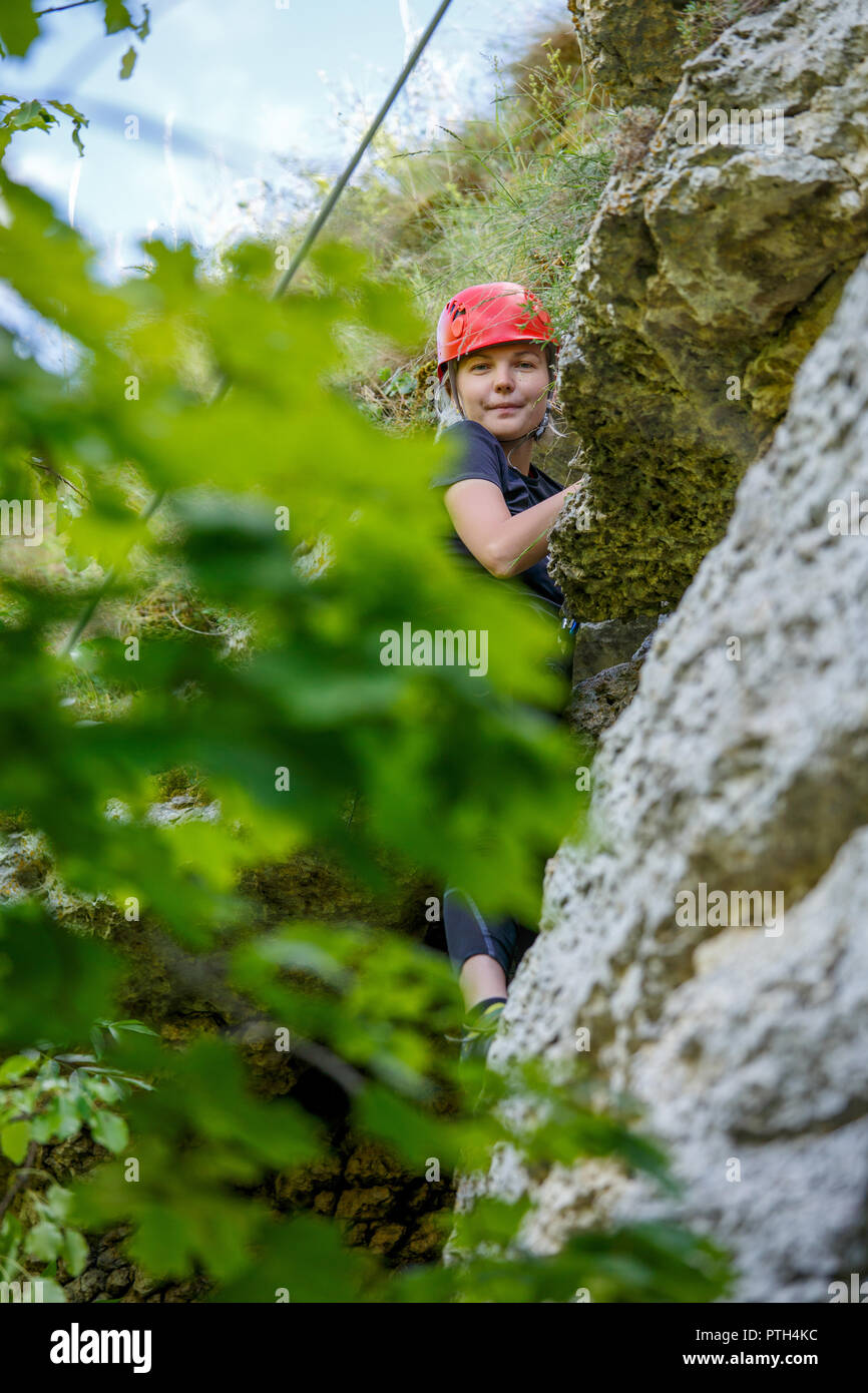 Photo de fille en rouge grimpeur helmet on mountain Banque D'Images