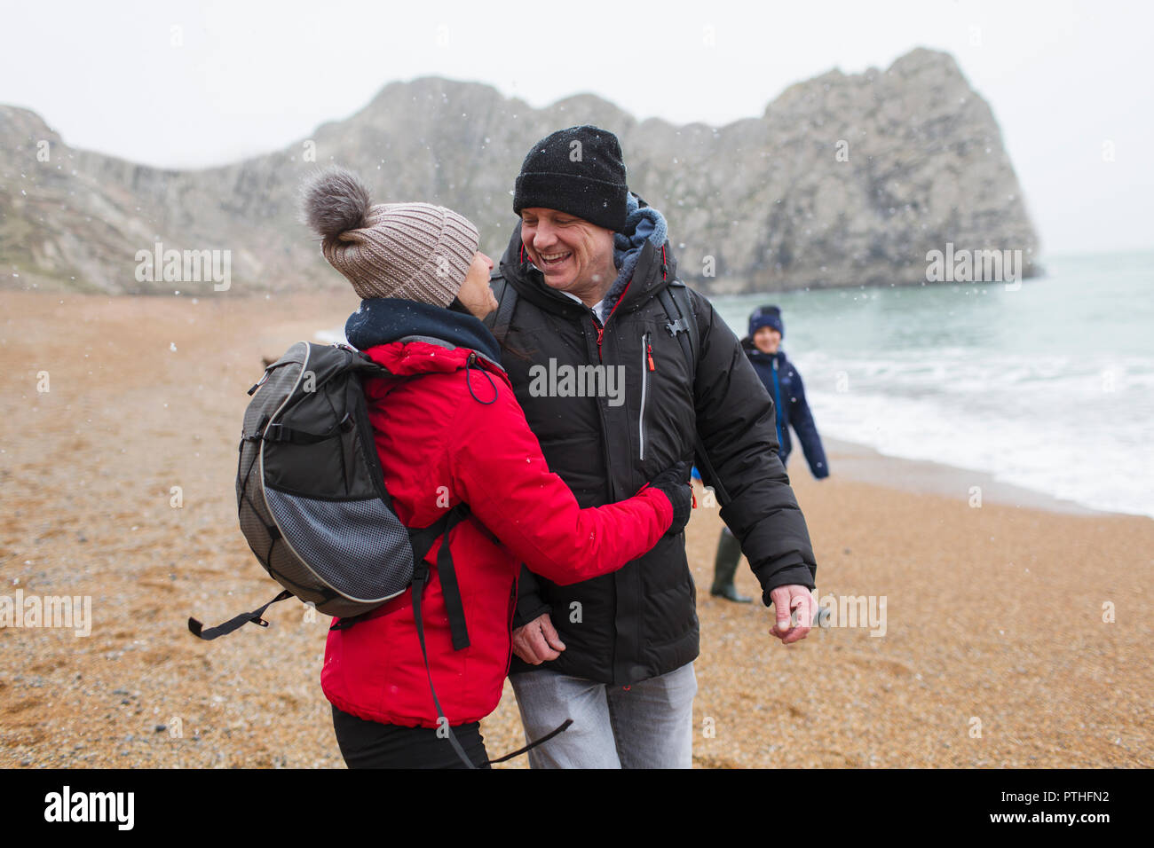 Affectueux, couple heureux dans des vêtements chauds d'hiver enneigés sur beach Banque D'Images