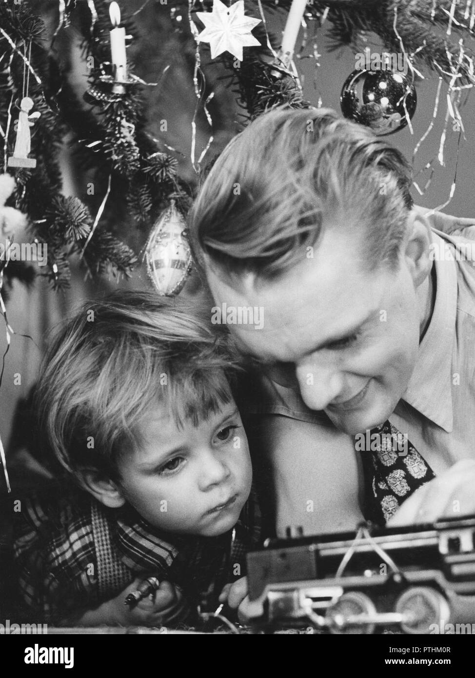 Noël dans les années 40. Un père et son fils jouent avec un jouet machine à vapeur par l'arbre de Noël. Suède 1940 Banque D'Images
