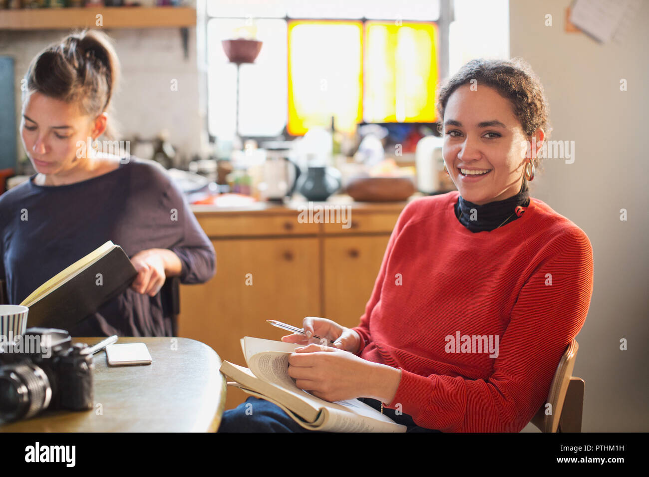 Portrait of smiling female college student studying at table de cuisine dans l'appartement Banque D'Images