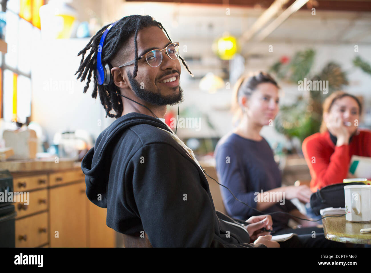 Portrait of smiling young man with headphones à table de cuisine Banque D'Images