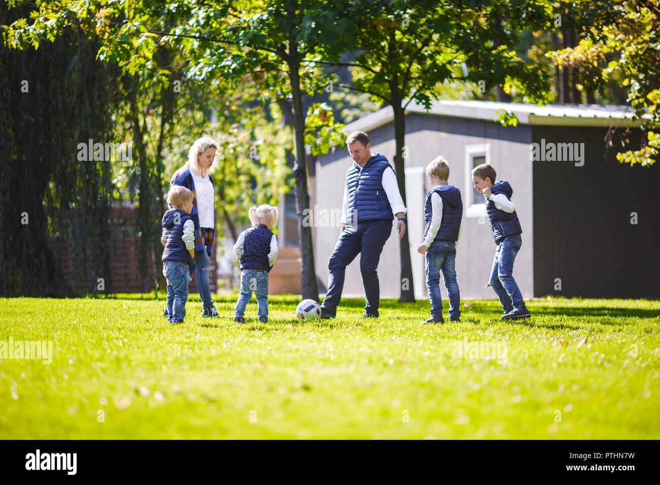 Le thème famille Activités en plein air. big friendly Caucasian family de Papa maman six et quatre enfants jouant au football, exécutant avec la balle sur la pelouse, g Banque D'Images