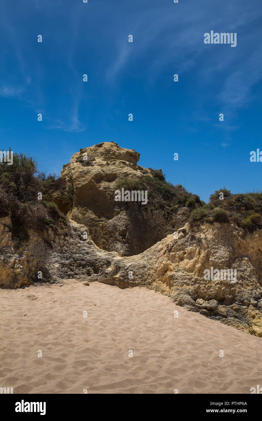 Le sable doré de la plage, entouré de falaises. Ciel bleu avec quelques nuages blancs. Gale, Algarve, Portugal. Banque D'Images