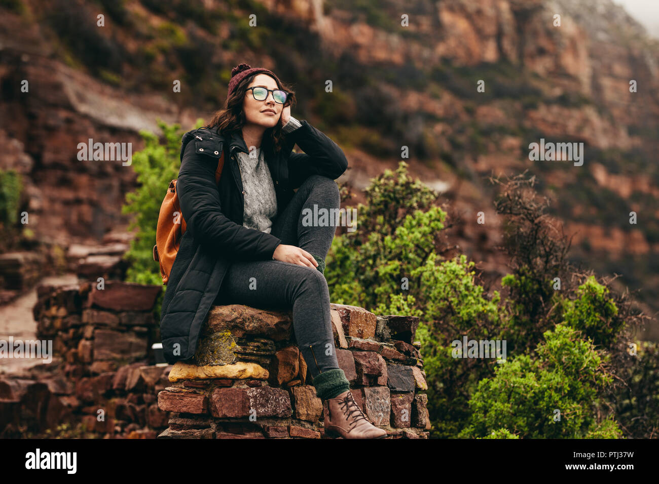 Femme assise détendue sur le côté de la colline et en regardant le paysage. Voyageur femelle assis sur une montagne de pierres avec en arrière-plan. Banque D'Images