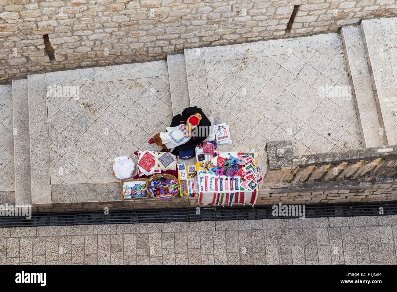 Une femme assise sur les marches en Dubrovniks vieille ville maison de vente de souvenirs. Banque D'Images