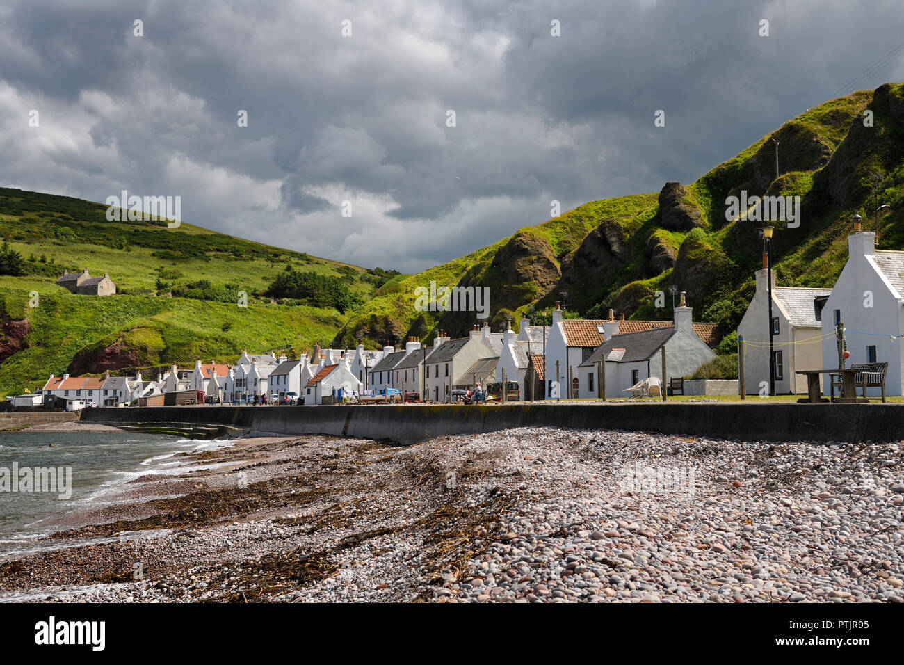 La plage de pierre et rangée de maisons blanches de Pennan coastal village de pêcheurs sur la mer du Nord dans l'Aberdeenshire Ecosse UK avec des falaises de mer verte Banque D'Images