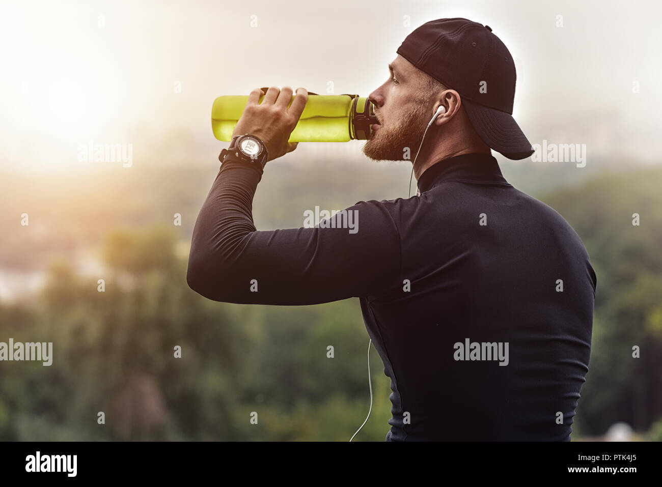 Gros plan homme sportif barbu se reposer et boire de l'eau après une séance d'entraînement. Banque D'Images