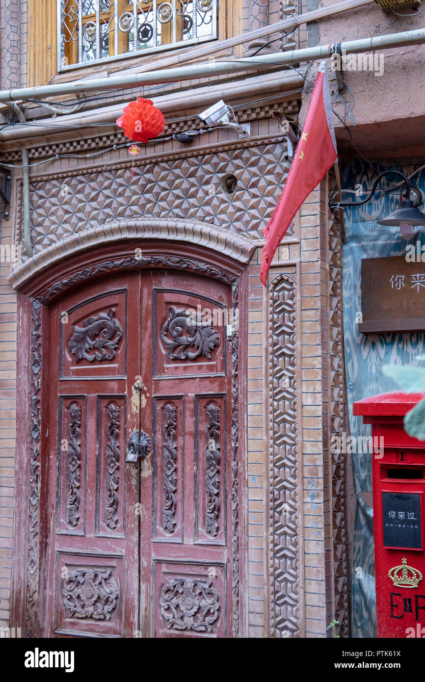 Caméra de sécurité et drapeau chinois plus cadenassé la porte en bois dans la vieille ville de nouveau voisinage Uigher à Kashgar, ou Kashi, Xinjiang, Chine. Banque D'Images