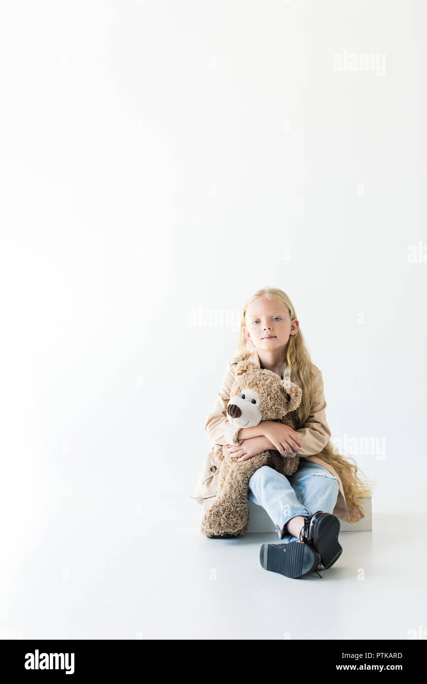 Vue magnifique sur toute la longueur du petit enfant teddy bear and smiling at camera while sitting isolated on white Banque D'Images