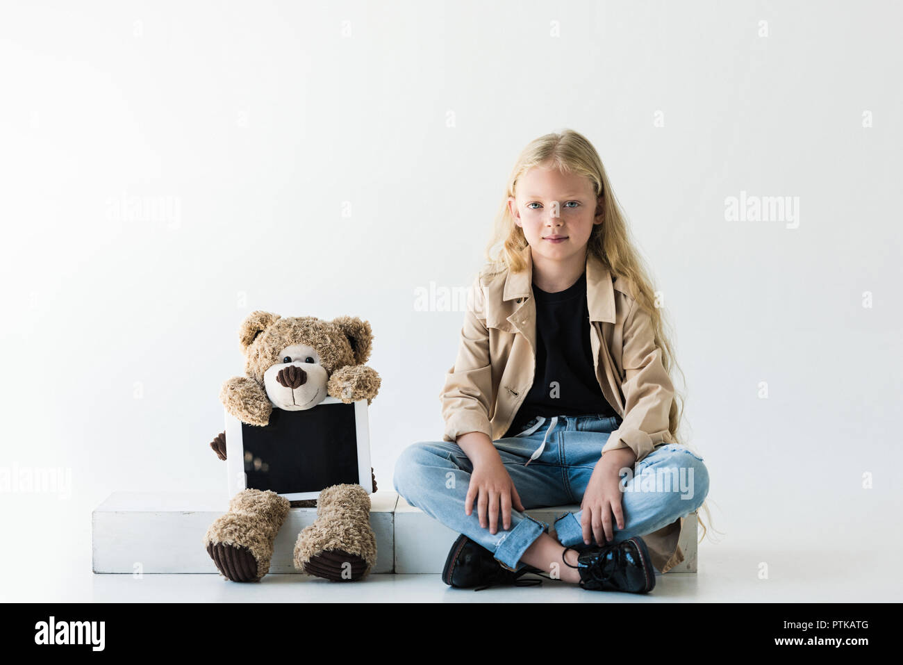 Teddy Bear with digital tablet et beautiful smiling kid élégant avec de longs cheveux bouclés on white Banque D'Images