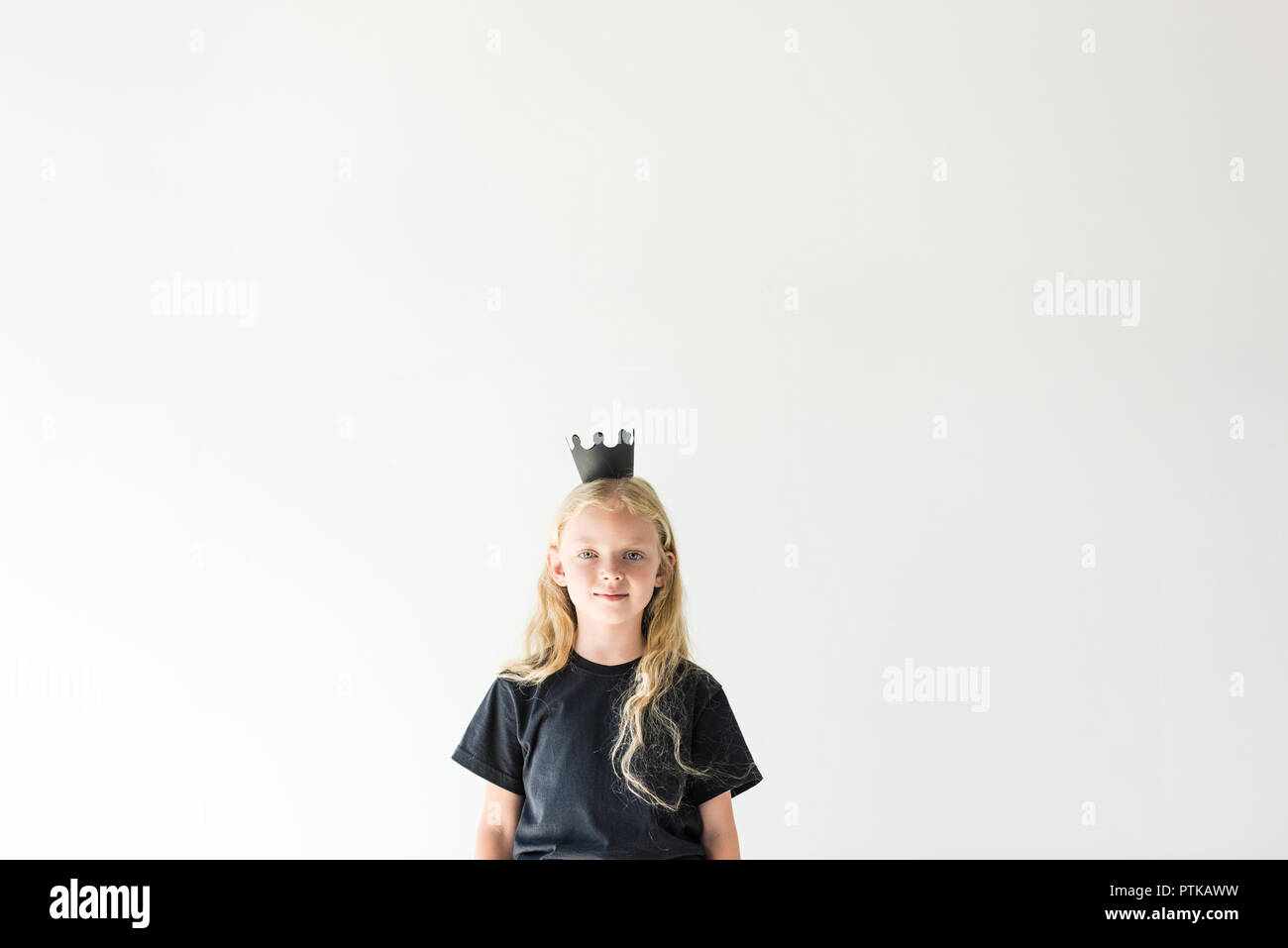 Adorable enfant avec de longs cheveux bouclés vêtu de noir et d'entendre smiling at camera isolated on white Banque D'Images