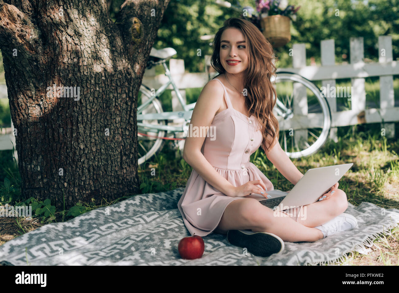 Cheerful young woman resting on tree sous couverture avec location garée derrière à campagne Banque D'Images