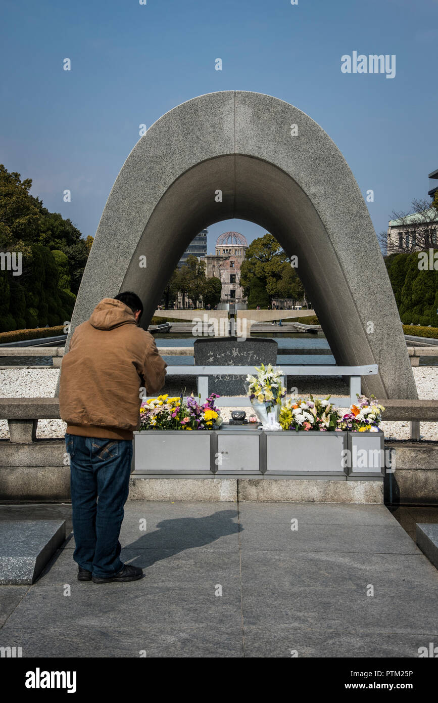 Un homme prie au cénotaphe monument à la mémoire des victimes de la bombe atomique qui a explosé sur Hiroshima au Japon. Banque D'Images