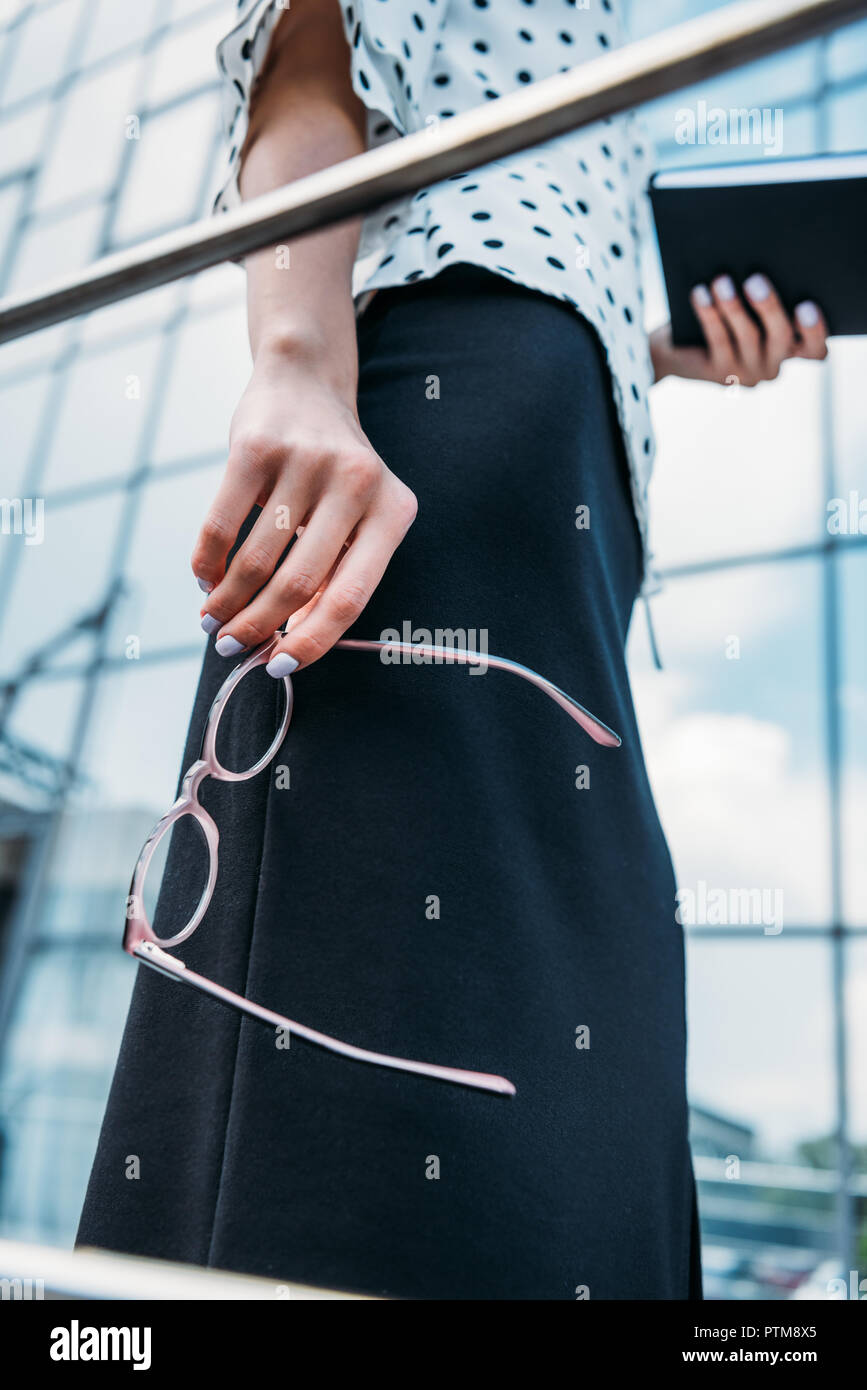 Vue partielle de businesswoman avec lunettes et ordinateur portable dans les mains debout sur street Banque D'Images